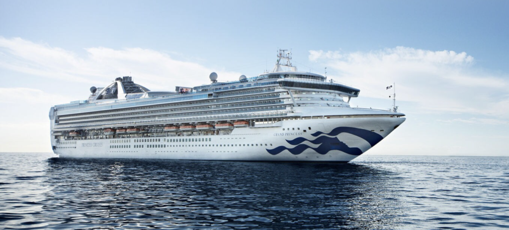 An image of a large cruise ship on the ocean, the ship is branded Princess Cruises. The sea is calm, the sky is a little cloudy.