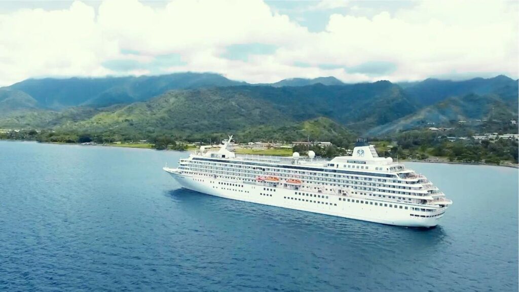 Cruise ship Crystal Serenity photographed from above, in a body of water with land behind